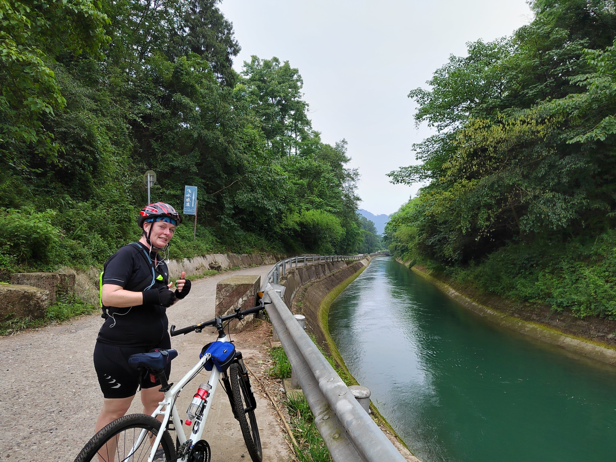 Traveler with a bicycle beside a tree-lined canal