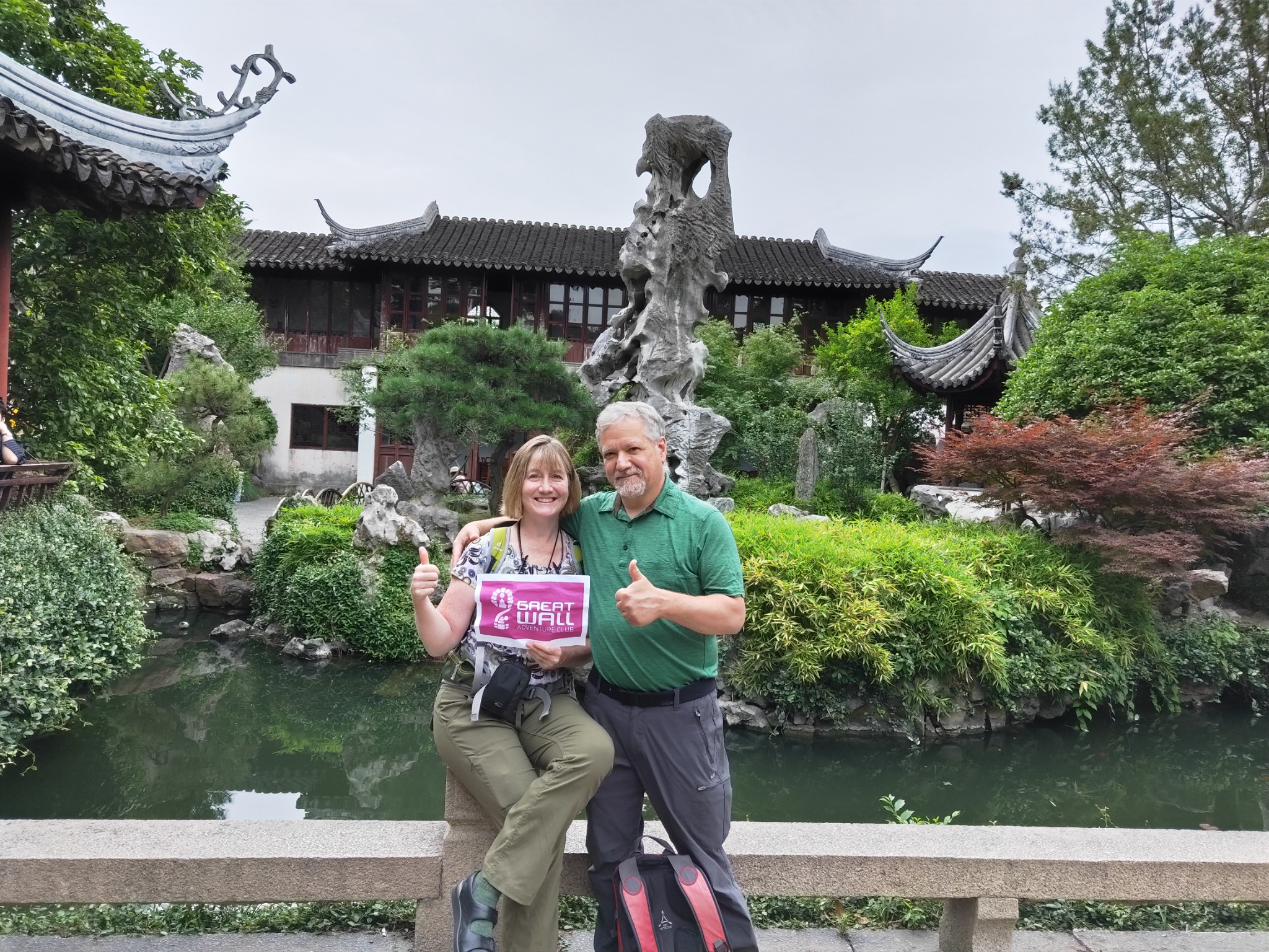 Two travelers beside a pond and rockery in a classical Chinese garden