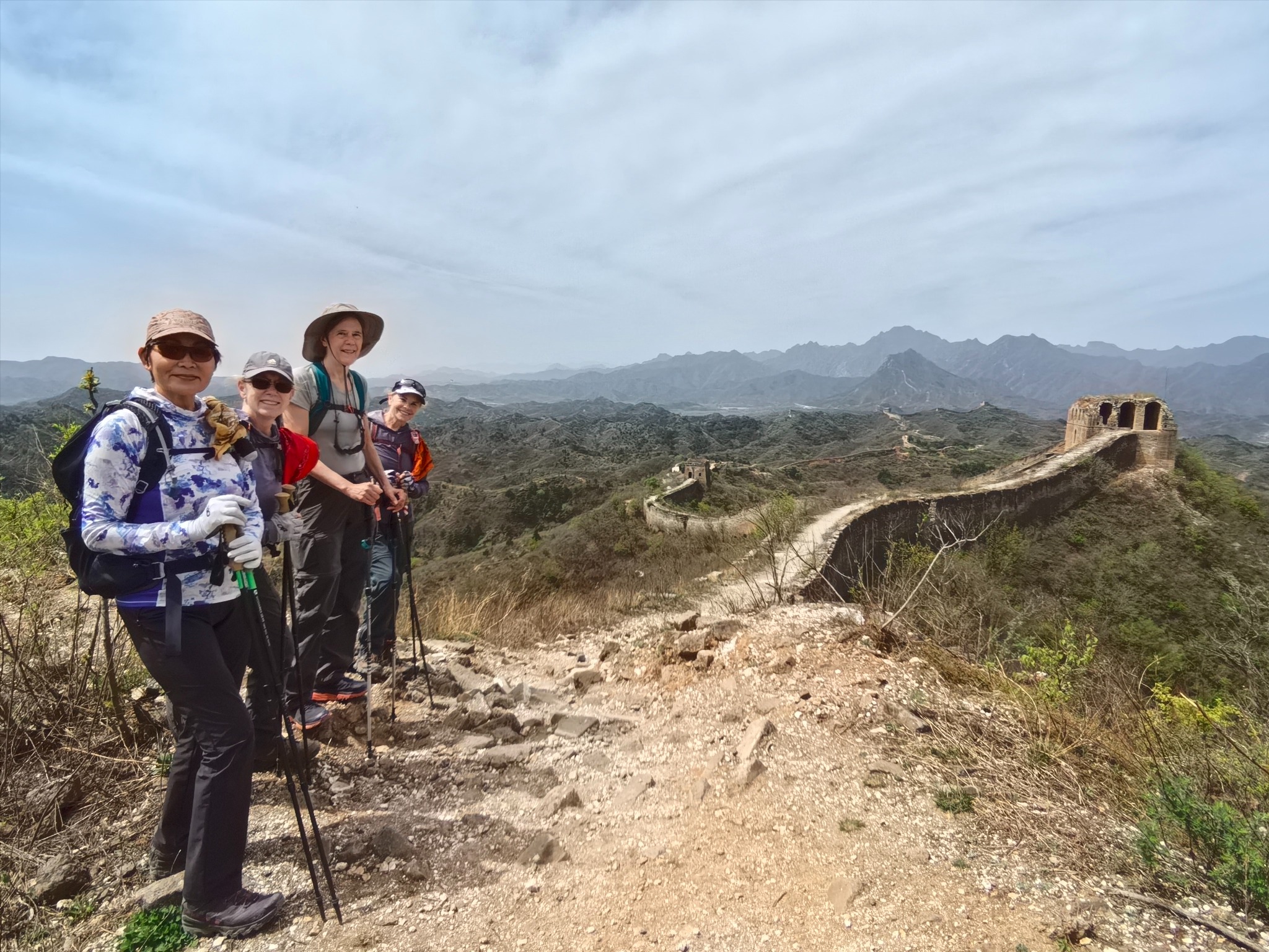 Two hikers on a trail beside an unrestored section of the Great Wall