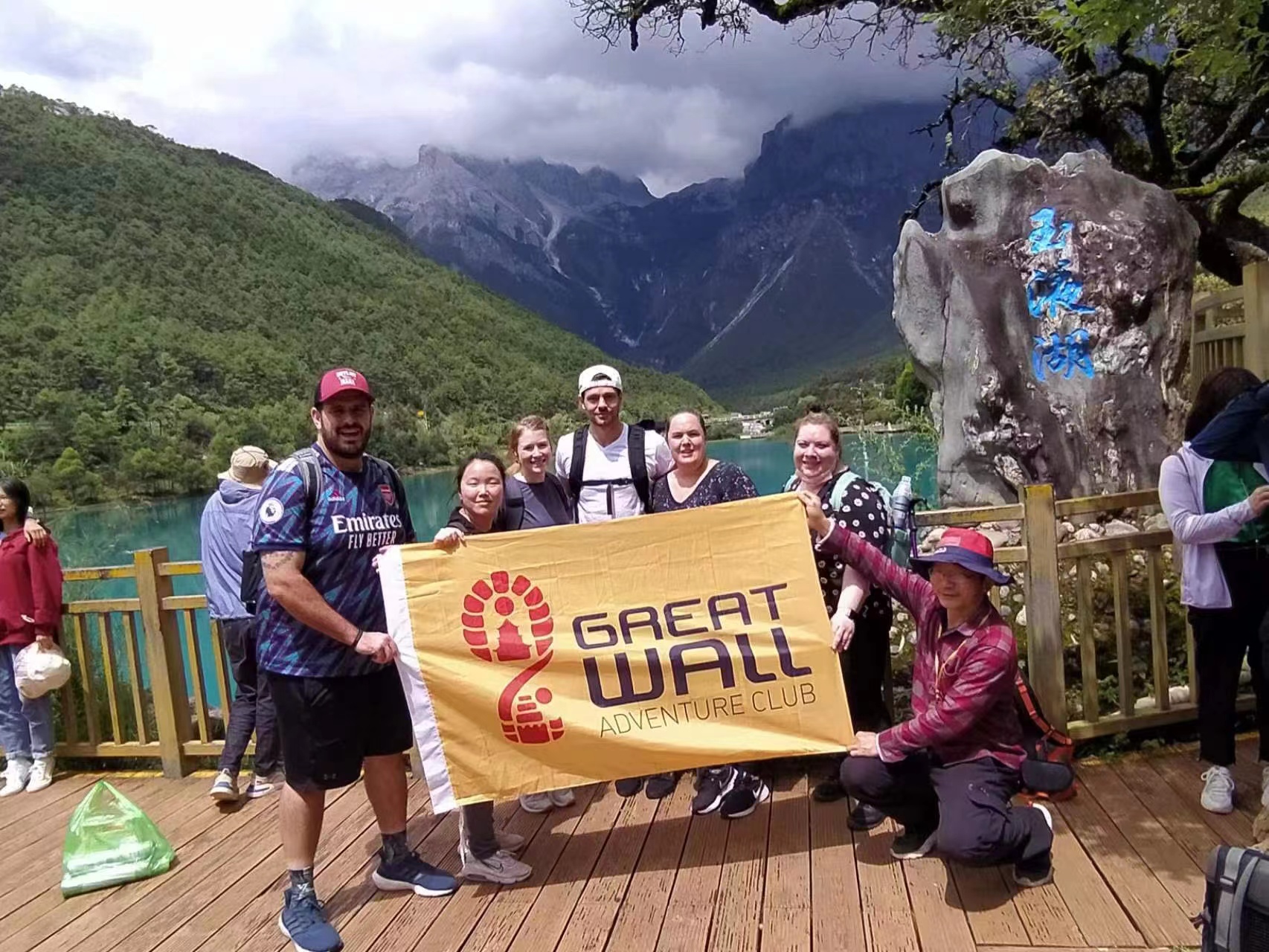Travelers holding a Great Wall Adventure Club banner at a mountain viewpoint