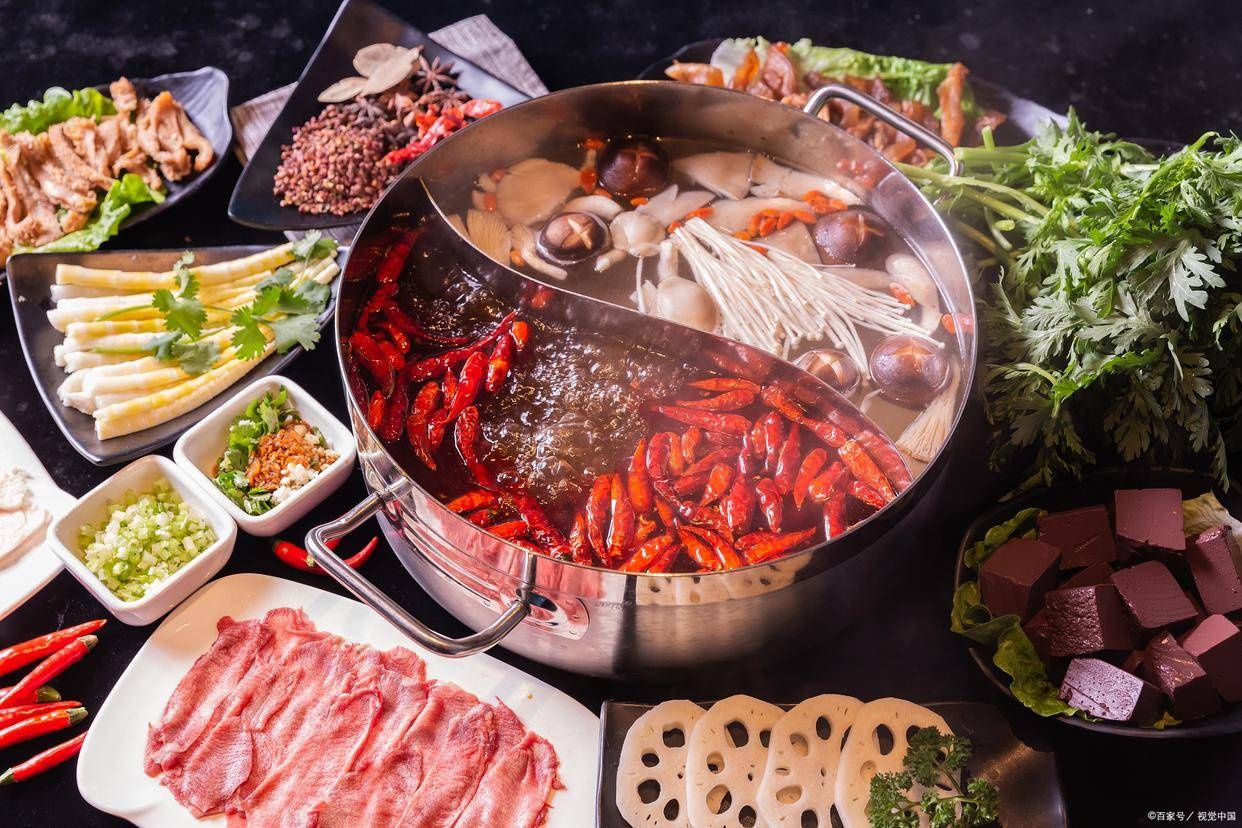 Chinese hot pot with spicy and mild broths, fresh vegetables, and sliced ingredients