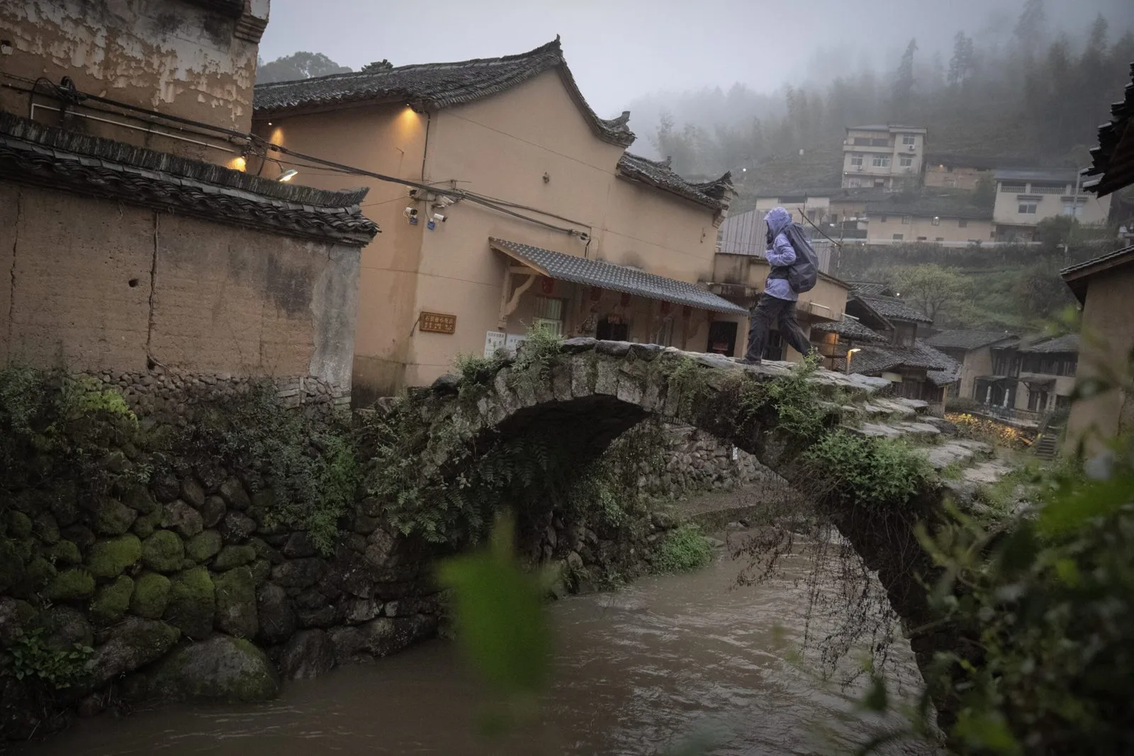 Hiker crossing a centuries old stone bridge in Songyang, Zhejiang.